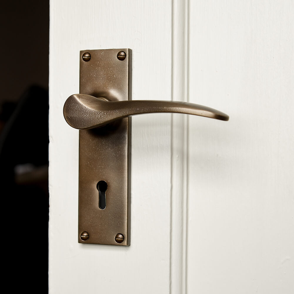 Brass door handle with curved lever on a cream door