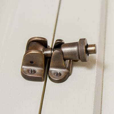 sash fastener in a distressed antique brass finish