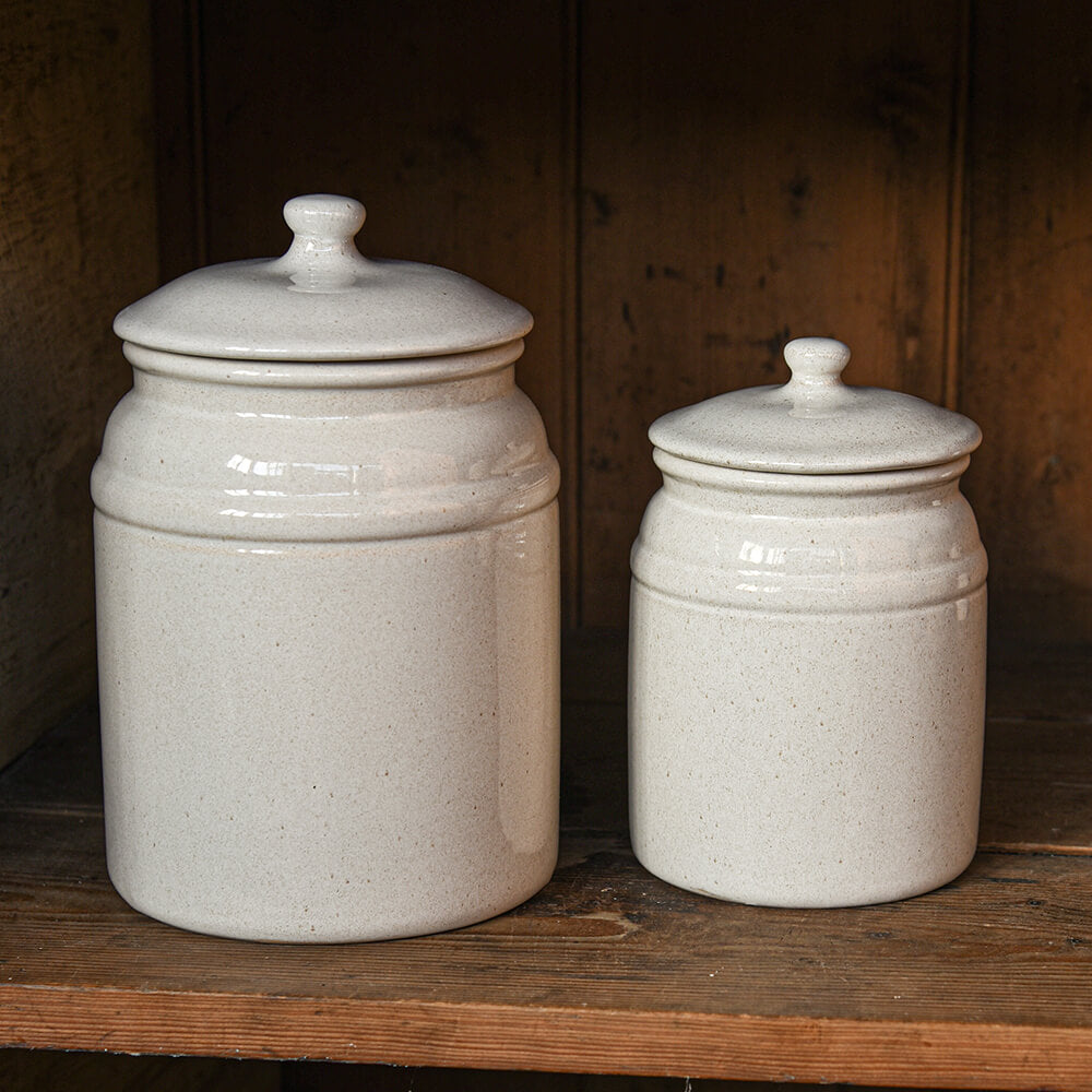 Two cream canisters o a shelf