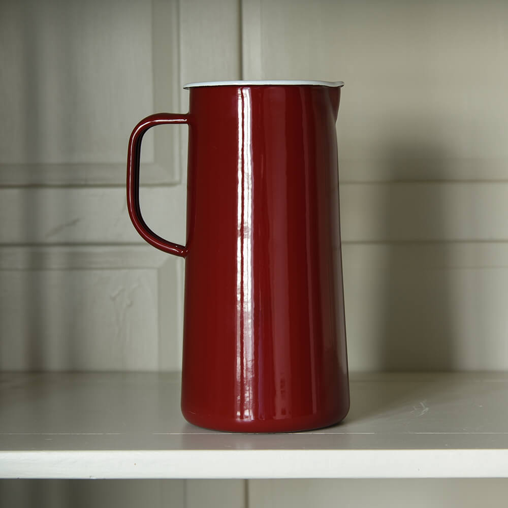 Enamel jug in burgundy red on a shelf