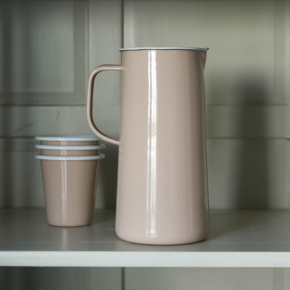 PInk enamel jug and cups on a shelf in a dresser
