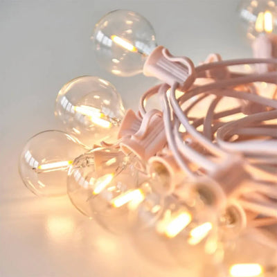 Pink festoon cable with lit bulbs coiled into a pile