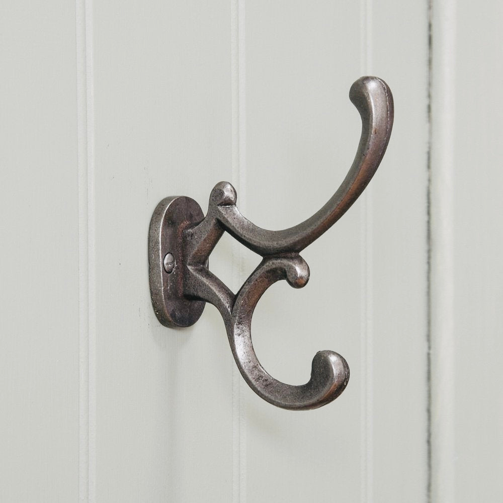 Ornate cast iron coat hook on a cream wall