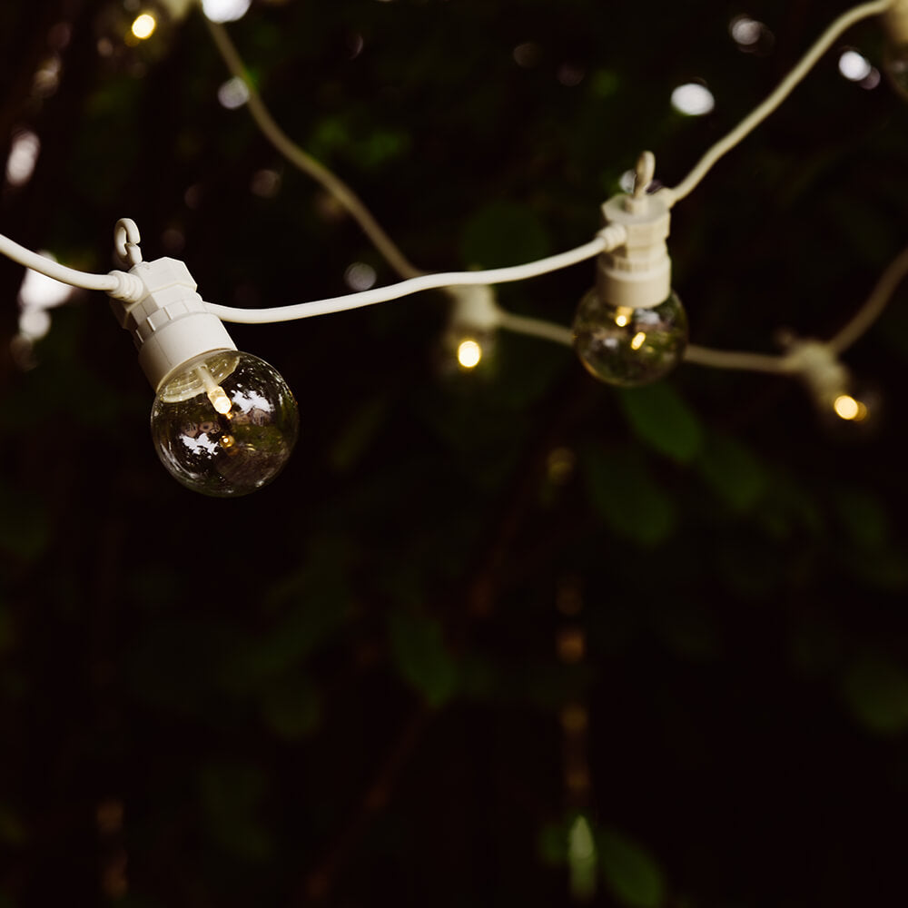 White golf ball festoon lights hung under trees