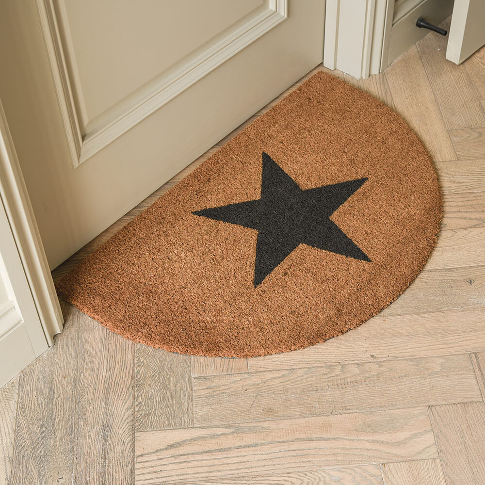 Doormat with a black star design on a wooden floor.