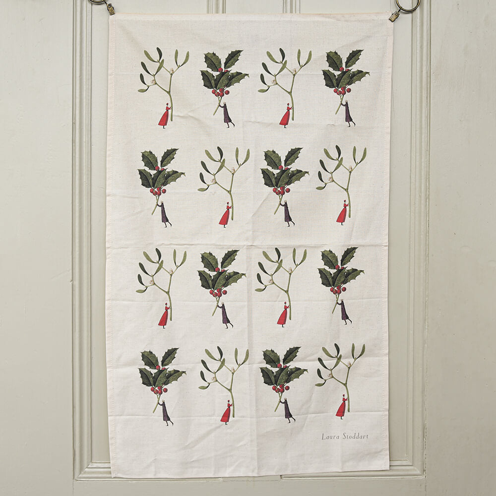Tea towel on a door with little illustrations of ladies holding holly sprigs