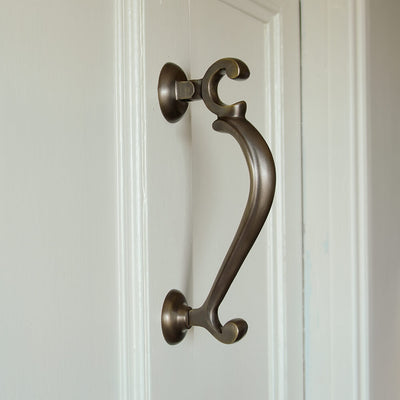 Large-Distressed-Antique-Brass-Doctors-Door-Knocker on cream door seen from the side