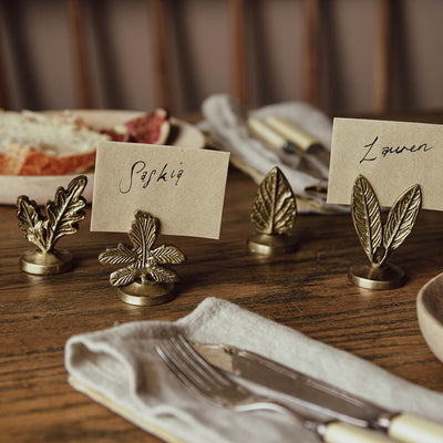 Brass leaf shaped card holder on a table displaying names