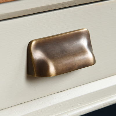 Brass cabinet handle on a taupe drawer