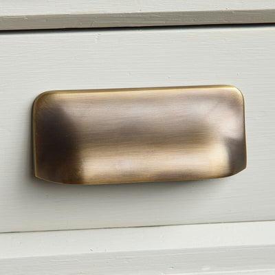 Brass rectangular handle on a taupe wooden surface