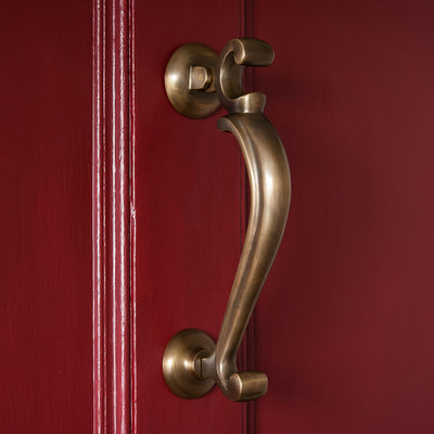 Light Antique Brass door knocker 0n a red door 