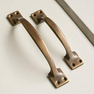 Two long handles in an antique brass colour showing two sizes beside each other 
