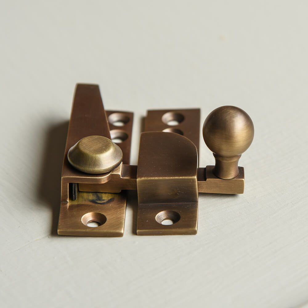 Brass window fastener on a light taupe background
