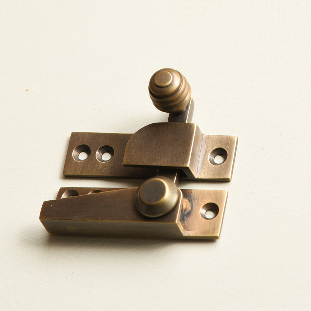 Brass window fastener on a light grey background