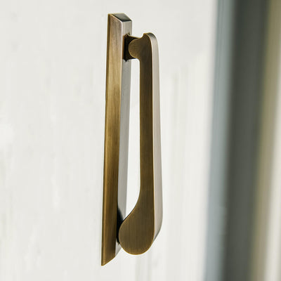 Slim door knocker in an elongated rectangular design shown from the side profile with a curved striker on integral backplate