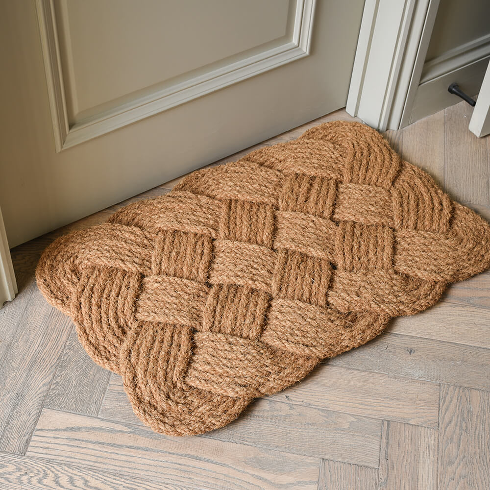Beige braided doormat on a wooden floor

