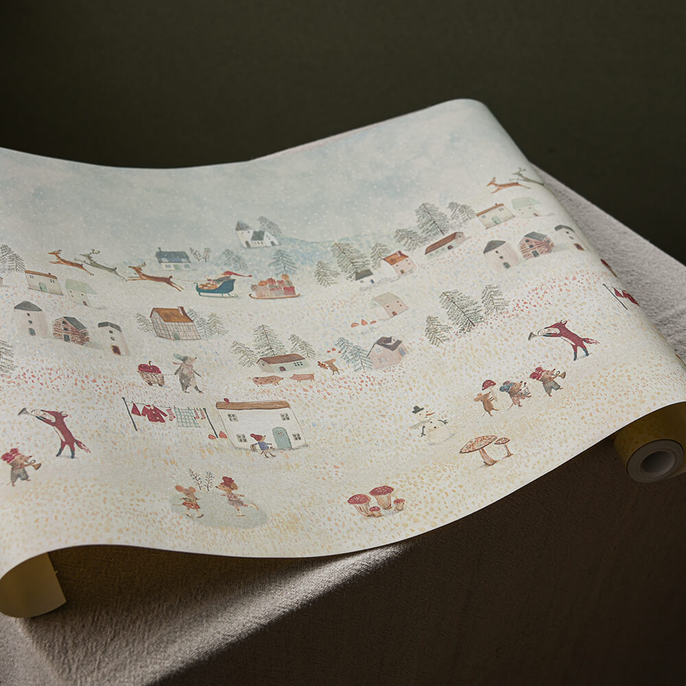 Roll of wallpaper with a winter village design on a dark surface