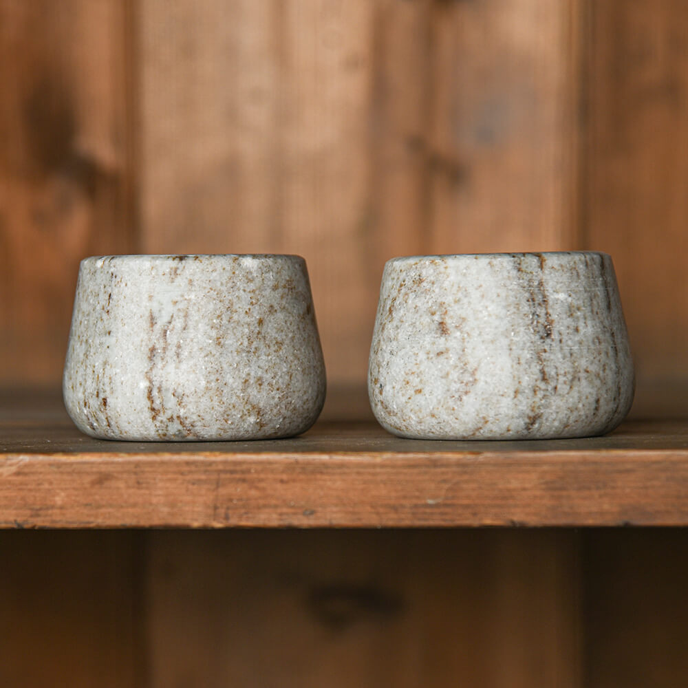 Two marble pots on a wooden surface with a wooden background