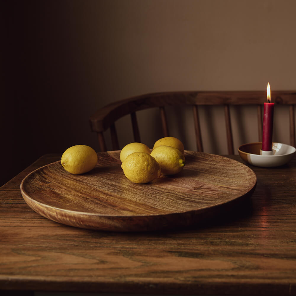 Woodn plate with lemons on a table with candle light
