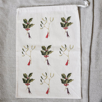 Bag with sprigs and miniature people on a beige background