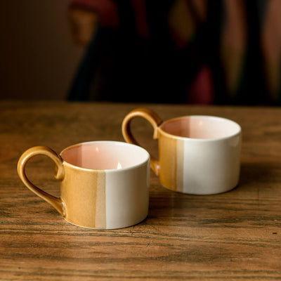 Set of 2 white and terracotta tealight holders with handles on wooden table with candles inside
