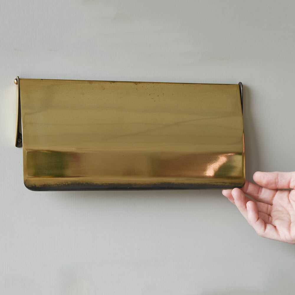 Brass letter tidy held by a hand against a neutral background