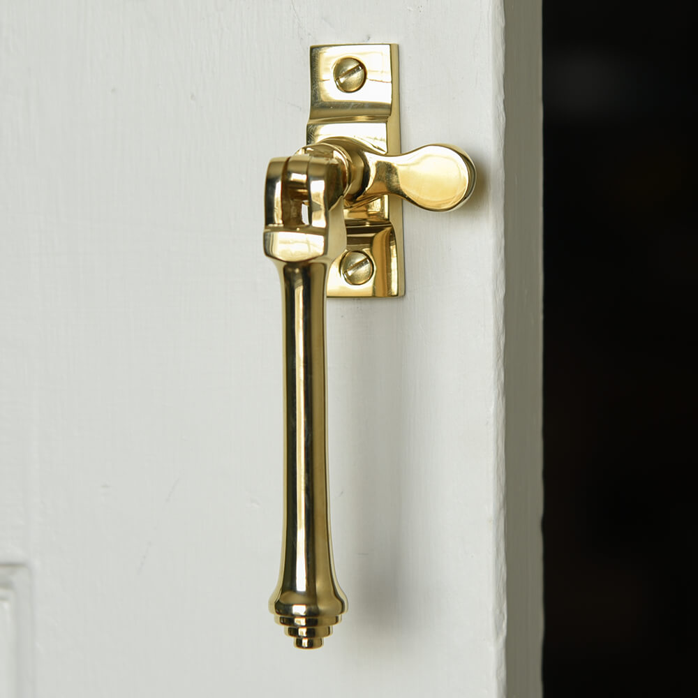 Polished Brass Casement window fastener with long drop pull that has reeded detail to the bottom with the hook on display