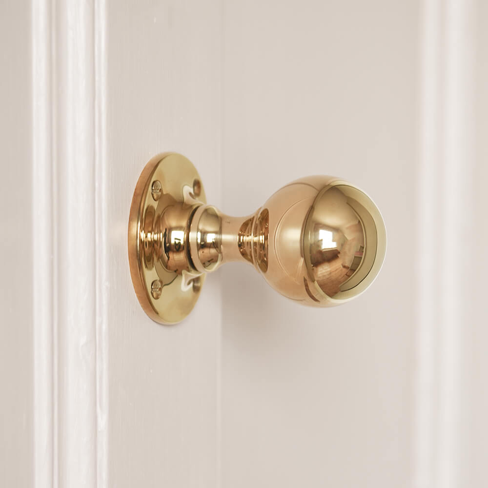 Brass round door knob on pink door