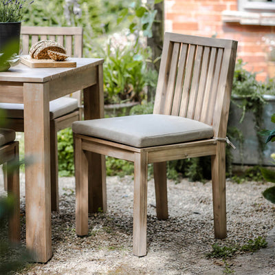 Porthallow dining chair with cushion beside a matching table in a garden setting