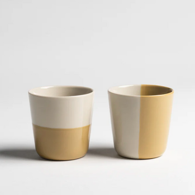Two ceramic cups with a two-tone design on a light gray background