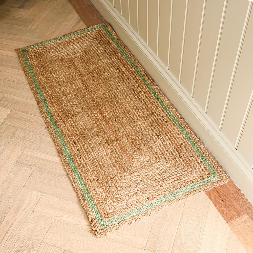 Woven mat with green border on a wooden floor