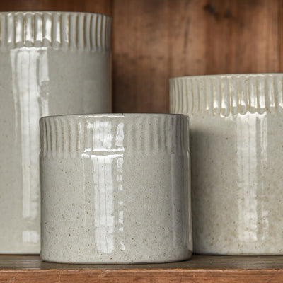 Three textured ceramic pots on a wooden surface with a wooden background