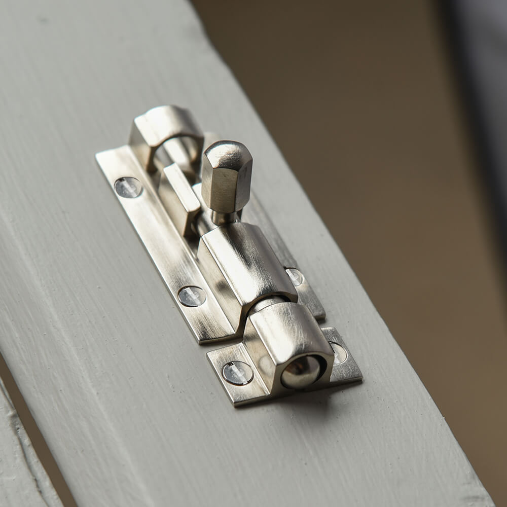 Small satin nickel bolt on a grey door
