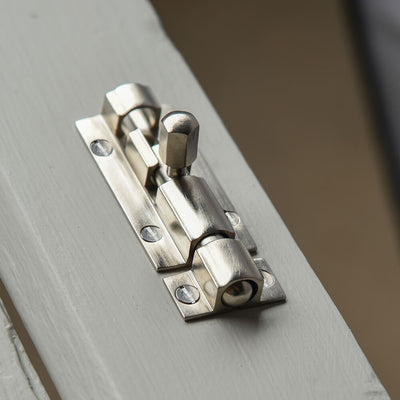 Small satin nickel bolt on a grey door