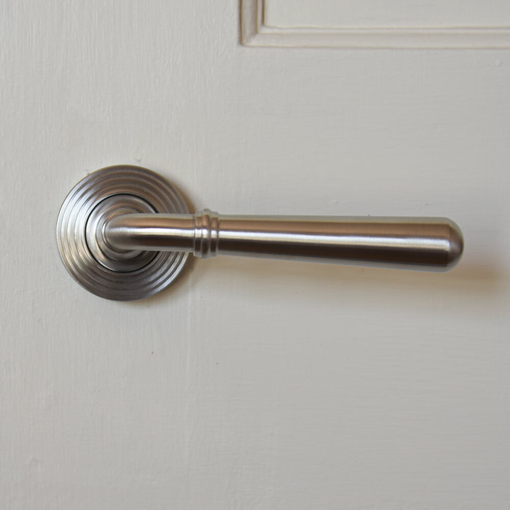 Satin stainless steeel lever handle with reeded backplate on cream door