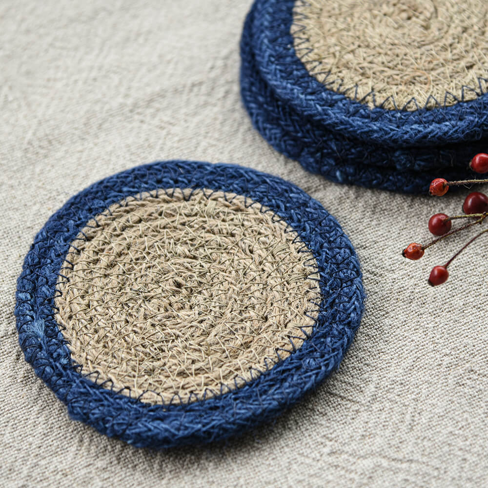Round woven coasters with blue outer rim on a textured surface