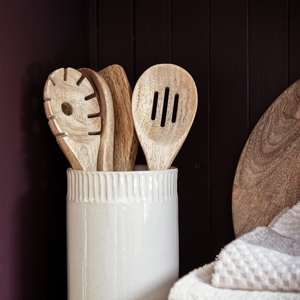 Set of wooden spoons in a white container against a dark wooden background