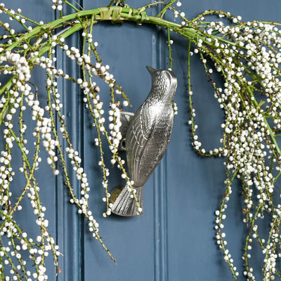 Decorative wreath with bird door knocker on a blue door