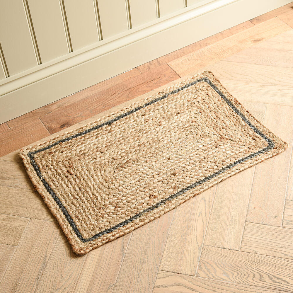 Rectangular jute rug with a blue grey border on a wooden floor.