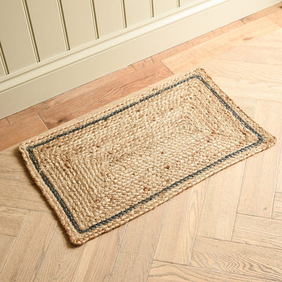 Rectangular jute rug with a blue grey border on a wooden floor.