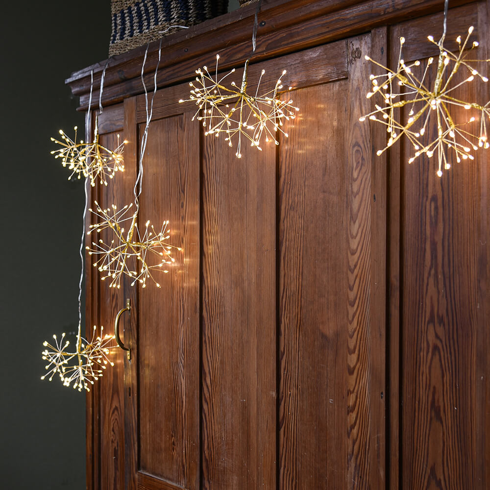 Decorative string lights shaped like starbursts hanging on a wooden surface.