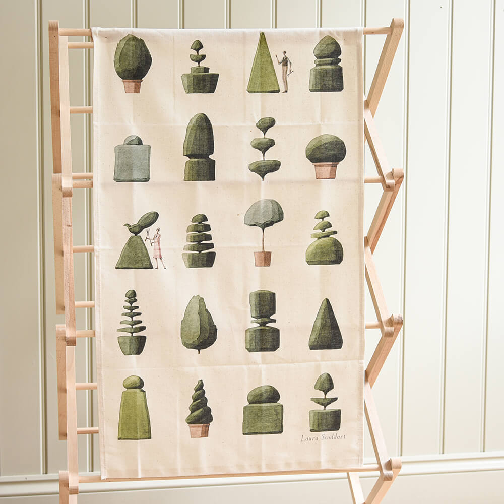Decorative towel with green geometric plant designs on a wooden ladder against a white wall.