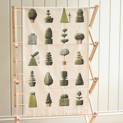 Decorative towel with green geometric plant designs on a wooden ladder against a white wall.