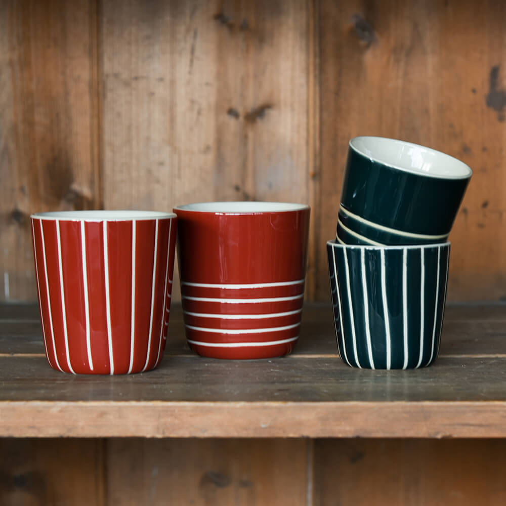 Striped ceramic beakers on a wooden shelf