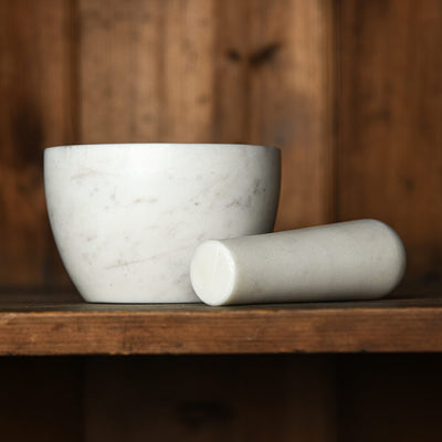 Marble mortar and pestle on a wooden surface with a wooden background