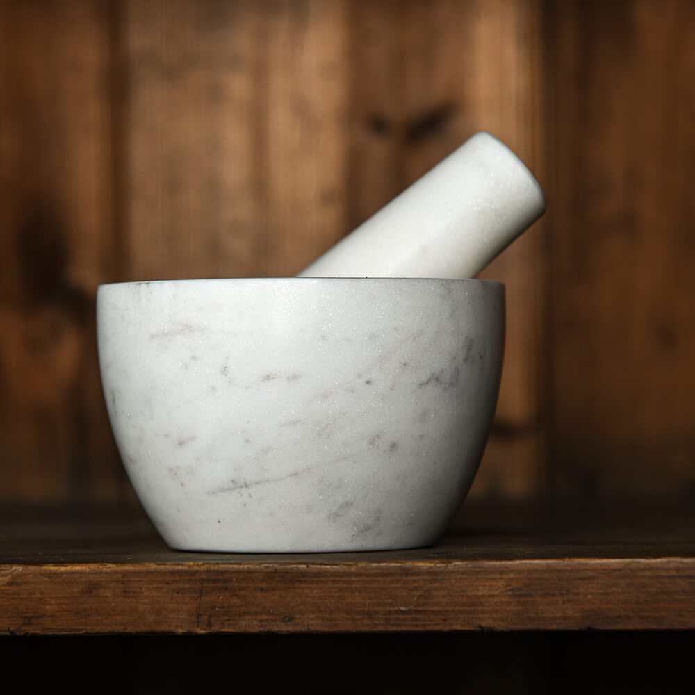 White marble mortar and pestle on a wooden surface with a blurred wooden background