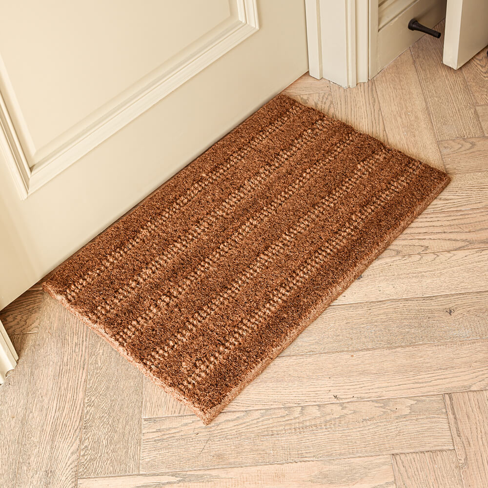 Brown doormat on a wooden floor next to a door