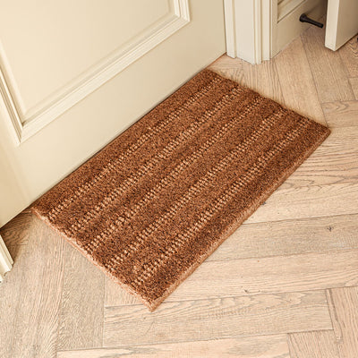 Brown doormat on a wooden floor next to a door