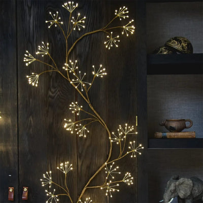 Decorative wall light fixture shaped like a branch with lights on a dark wooden wall.