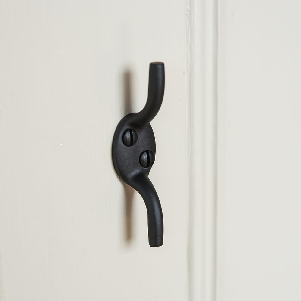 Black metal cleat hook on a white wooden door